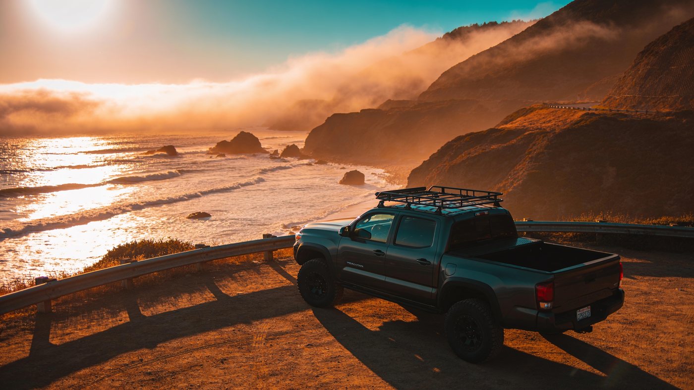 Overland truck parked at a Pacific coast cliff pullout at golden hour